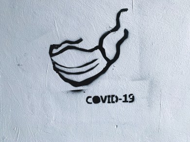 Graffiti style of a mask with COVID-19 written underneath.